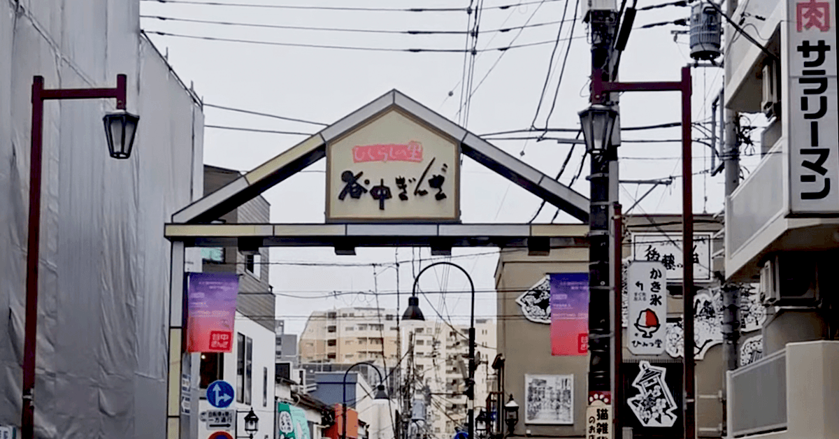 Entrance archway to Yanaka Ginza shopping street in Tokyo, with the street's name sign overhead