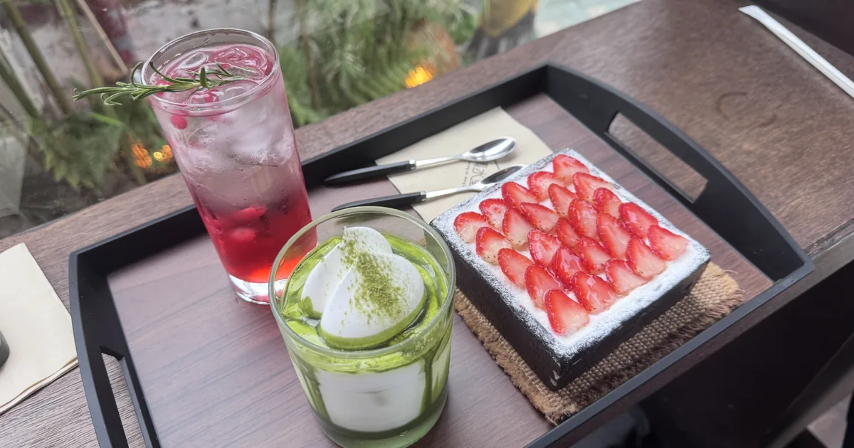 Matcha cream latte, strawberry cake, and a berry iced drink on a tray at a café in Seoul