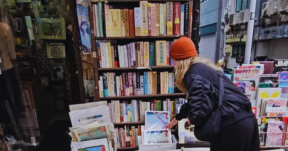 Woman browsing shelves of secondhand books at a street bookstall in Jimbocho, Tokyo
